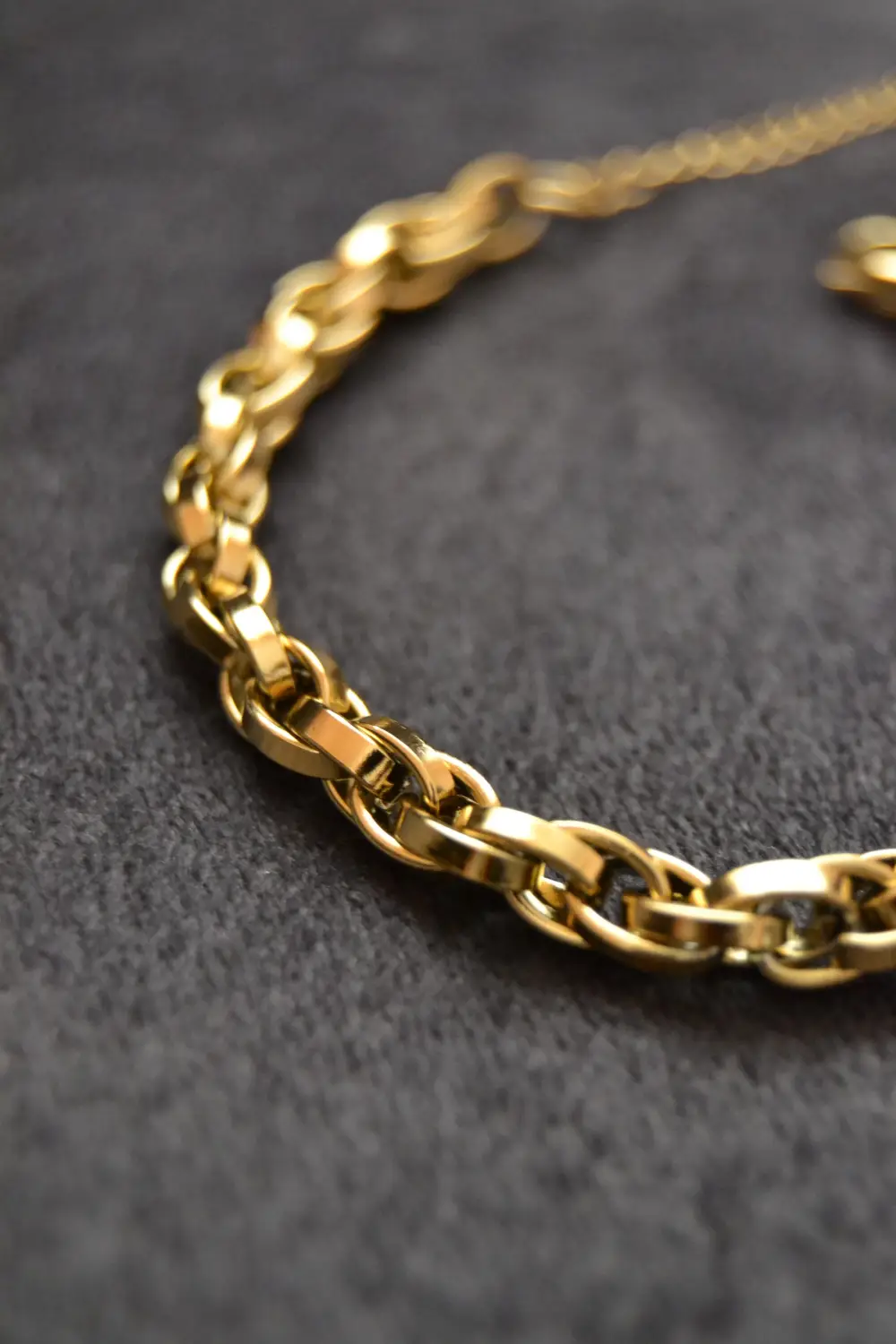 A gold chain lying on a grey cloth