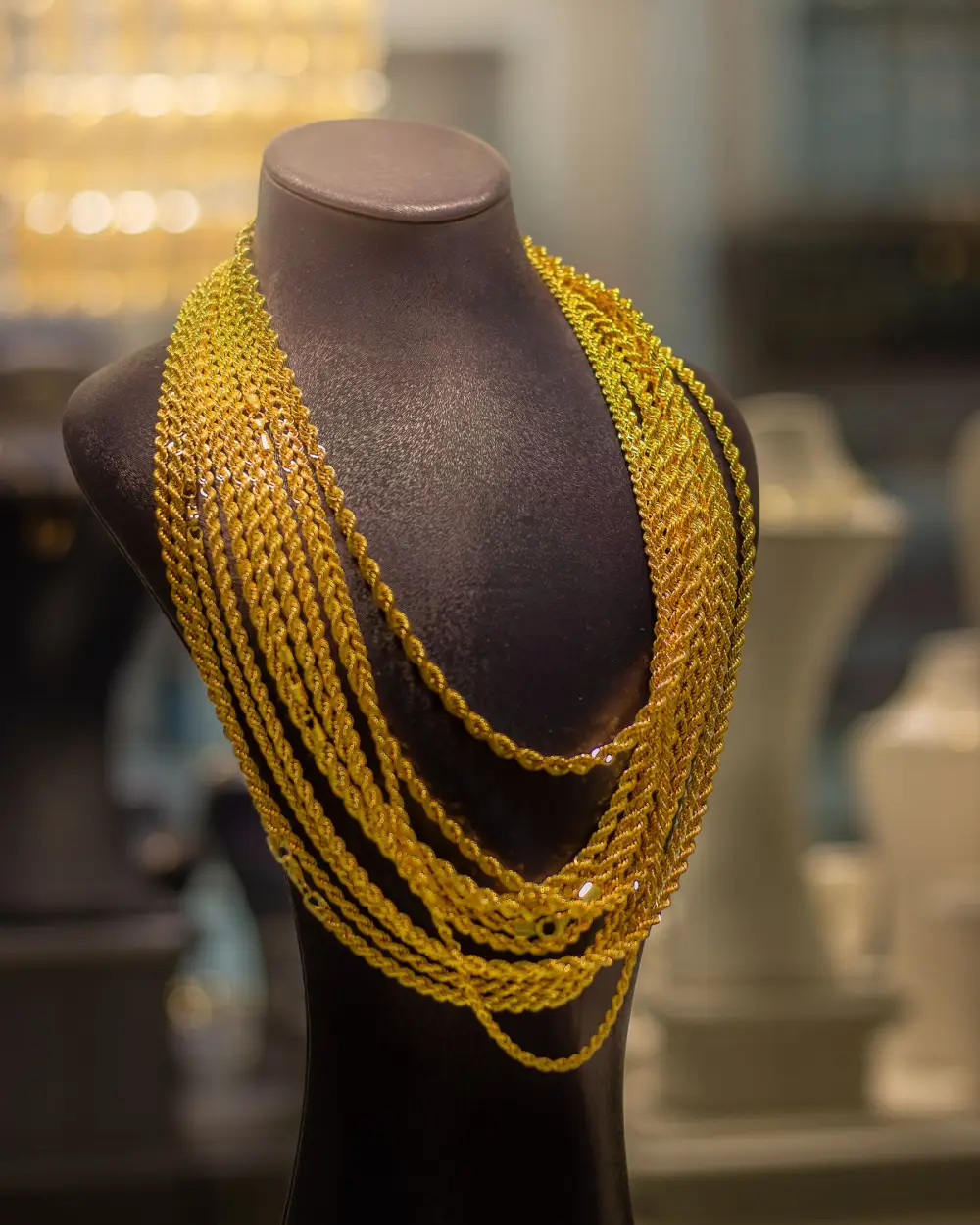 Long gold chains layered on a display bust in a jewellery shop