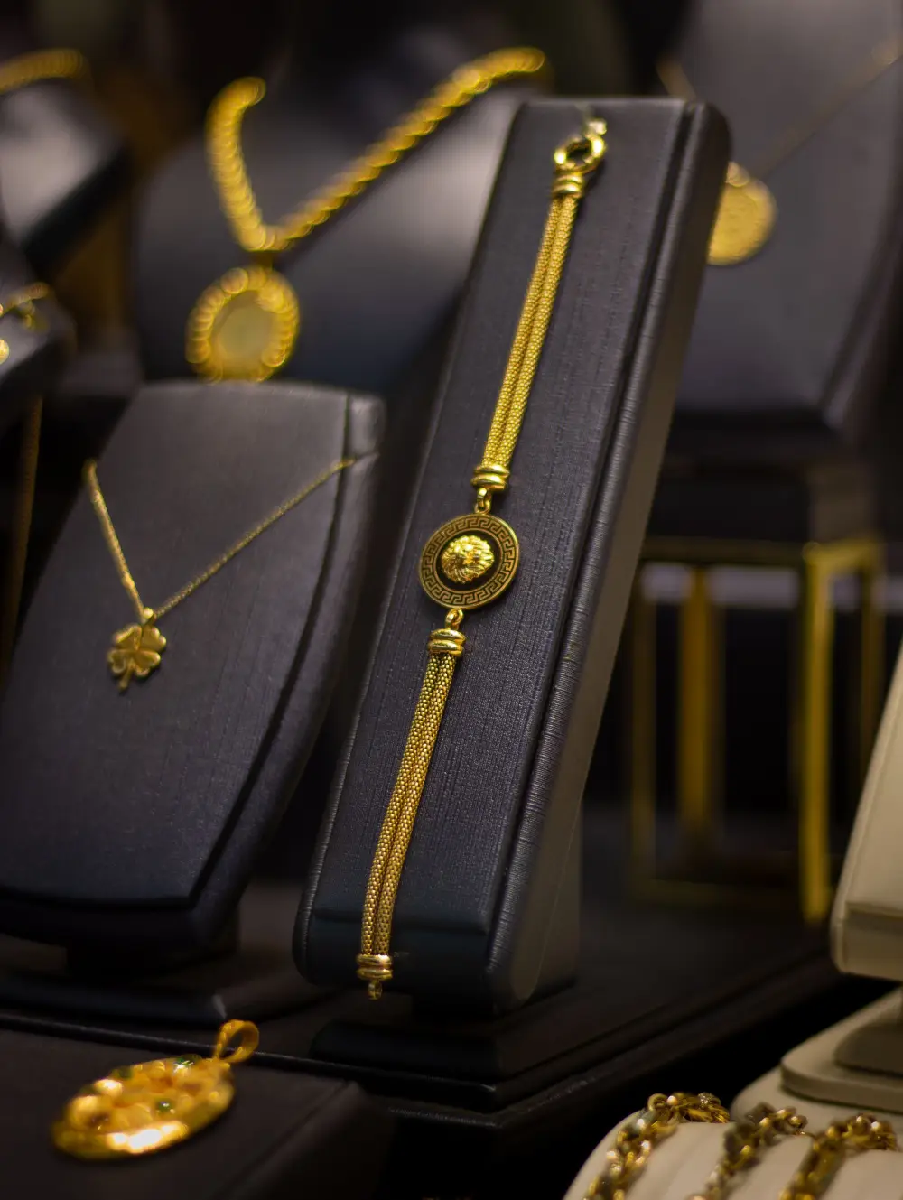 Gold necklaces and a bracelet on black display stands in a jewellery shop