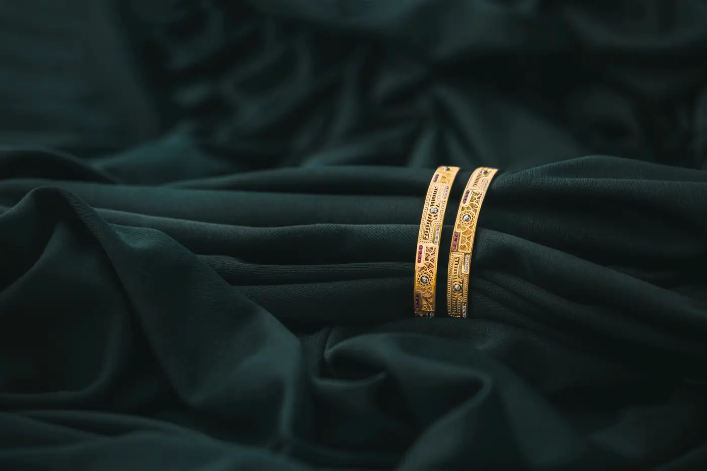 A pair of gold bangles on dark green cloth