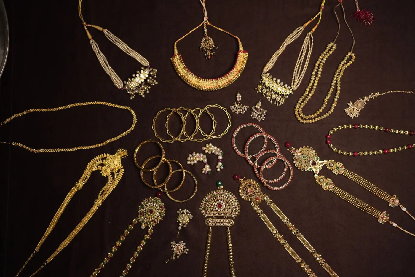 Traditional gold necklaces, bangles and chains laid out on a dark cloth